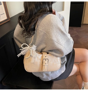 Detail of beige hobo shoulder bag with silver buckle and lace pearl bow accessory