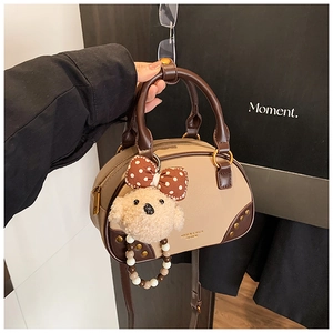 Detail of trendy color-block pillow bag with a plush puppy charm and beaded strap
