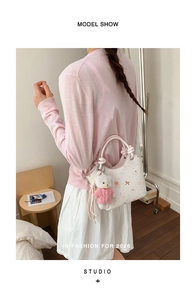 Detail showing white bucket bag with cute cartoon prints and pink woven handle on a model