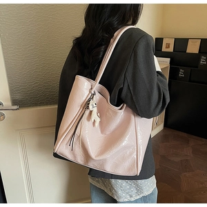 Detail of glossy pink wrinkled leather tote bag featuring a cute white puppy plush charm