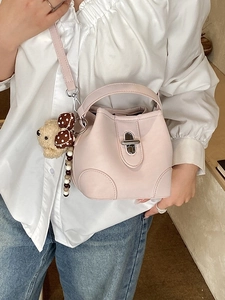 Minimalist light pink bucket bag with silver metal lock and cute bear charm worn by a model