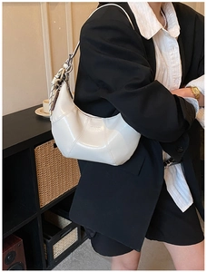 Close-up of a white crescent shoulder bag with vertical stitching and smooth glossy finish