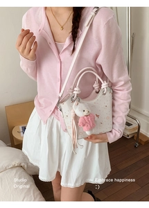 Detail of white floral bucket bag with pink handle and cute teddy bear plush charm
