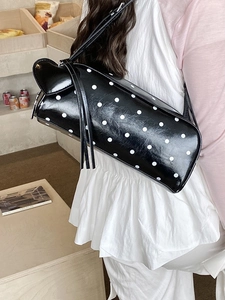 Polka dot underarm bag in black with white spots and long tassel decoration
