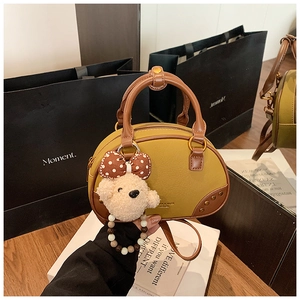 Close-up of yellow pillow bag featuring a plush bear charm and premium brown leather trim