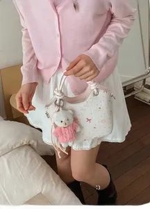 Detail of white bucket bag with pink bear print and cute knitted teddy charm accessory
