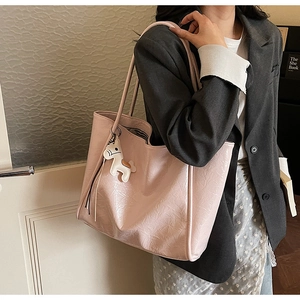 Detail of light pink wrinkled texture tote bag with a cute white horse charm on long strap