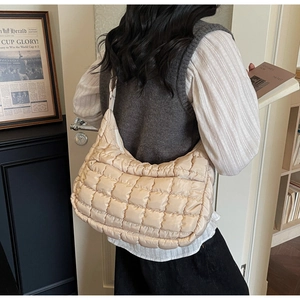 Close-up of beige quilted nylon shoulder bag with a textured square pattern and glossy finish