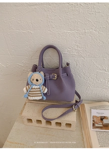 Close-up of a retro purple handbag with a cute bear pendant and golden buckle detail