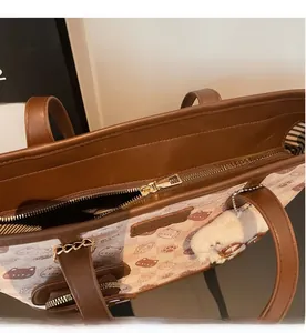 Dettaglio della cerniera dorata liscia su una borsa tote marrone con stampa di gatto