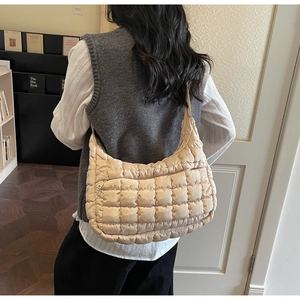Detailed back view of a beige quilted hobo bag with wide shoulder strap on a model