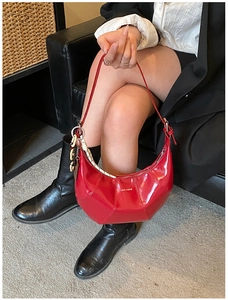 Close-up of red crescent moon bag with stitched leather, chain detail, and logo print