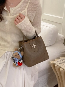 Brown lychee leather bucket bag with silver turn-lock and cute bear charm pendant
