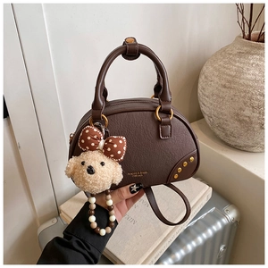 Detail of dark brown semi-circle handbag with lychee texture and plush dog pendant