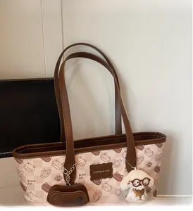 Dettaglio della borsa tote beige con stampa di gatto e ciondolo in peluche a forma di cane