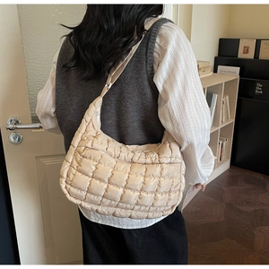 Detail showing beige quilted crossbody bag texture and metallic zipper on shoulder strap