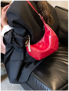 Detail of red glossy crescent shoulder bag with LOVE & DESIRE text on black blazer