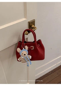Red retro leather handbag with plush charm hanging on vintage brass door handle