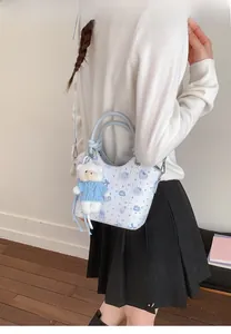 Close-up of light blue bucket bag with heart prints and white plush bear charm