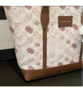 Dettaglio della borsa tote a scacchi rosa con stampa gatto e ciondolo morbido