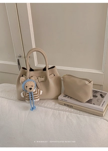 Detail of beige litchi grain bucket bag with matching pouch and plush bear charm