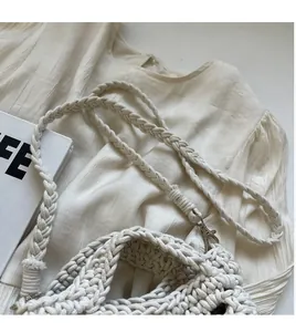 Close-up of beige hand-woven crochet bag with thick texture and metal hardware