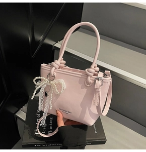 Détail du sac seau rose clair avec nœud en perles et dentelle et bandoulière réglable