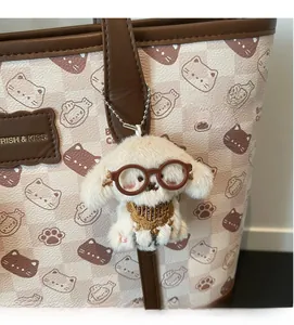 Dettaglio del carino ciondolo barboncino in peluche con occhiali e ricamo dorato