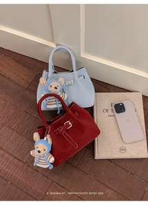 Detail of crossbody bucket bags in blue and red with cute bear charm and belt strap design