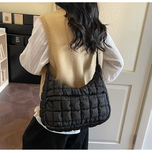 Close-up of black quilted puffer shoulder bag with a functional front zipper pocket