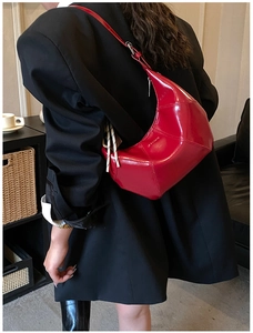 Detail of red patent leather shoulder bag with geometric stitching and glossy finish