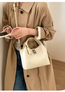 Chic beige leather bucket bag with silver lock worn with a khaki trench coat