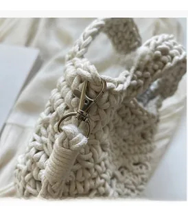 Detailed macro view of the cream woven texture and silver metal lobster clasp on the bag