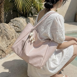 Light pink tote bag with shiny wrinkled texture and a white pony charm decoration