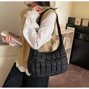Detail of black quilted cloud bag with padded diamond texture and wide shoulder strap