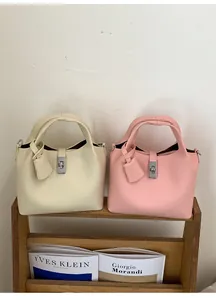 Detailed close-up of cream and pink bucket bags with pebble leather texture and metal locks