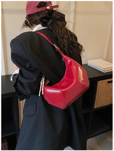 Chic red patent leather croissant bag shown on model with polished glossy finish