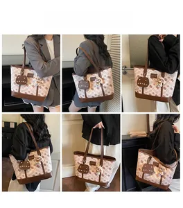 Dettagli di una borsa tote carina con stampe di gatti, manici in pelle e ciondoli morbidi