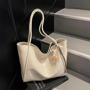 Minimalist beige oversized tote bag with pleated texture and white horse charm pendant