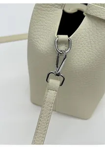 Close-up of silver metal clasp and leather stitching on the cream bucket bag