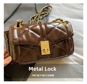 Detail of dark coffee quilted leather bag featuring a gold square twist lock and chain strap