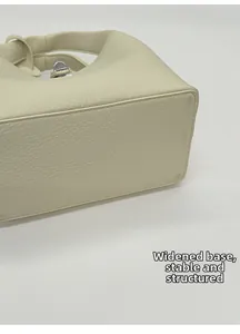 Macro shot of the widened base design on a cream-colored leather bucket handbag
