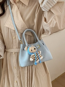 Light blue retro bucket bag with a knitted bear charm and adjustable shoulder strap