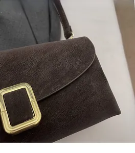 Gros plan d'un sac en similicuir marron mat avec une boucle métallique dorée élégante