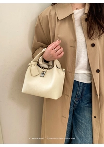 Detailed view of beige lychee texture leather bucket bag worn with a stylish trench coat