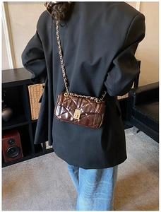 Detail of dark brown quilted leather crossbody bag with golden twist lock and chain strap
