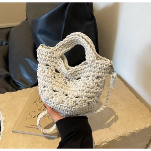 Detailed close-up of cream hand-woven straw bag texture with detachable shoulder strap