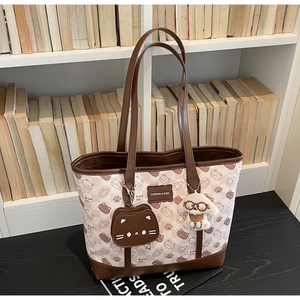 Dettagli di una borsa tote a scacchi con stampe di gatti e ciondoli di peluche