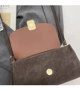 Gros plan détaillé du fermoir magnétique en métal sur un sac bandoulière marron vintage