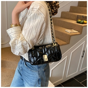 Detailed side view of black quilted crossbody bag with gold chain and twist-lock buckle